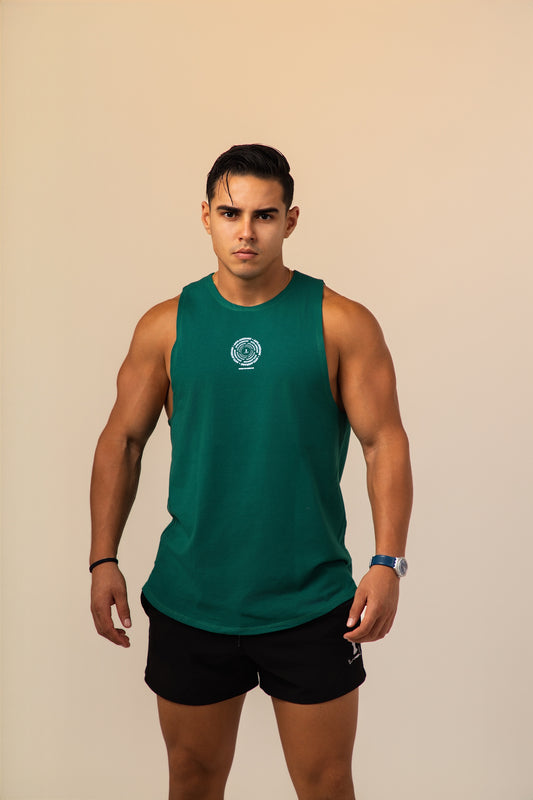 Man wearing a green sleeveless shirt and black shorts against a beige background